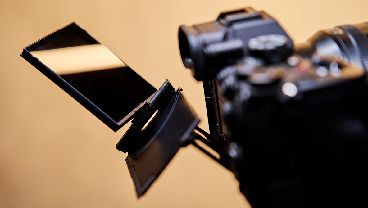 Camera flash diffuser attached to a DSLR camera against a warm beige background.