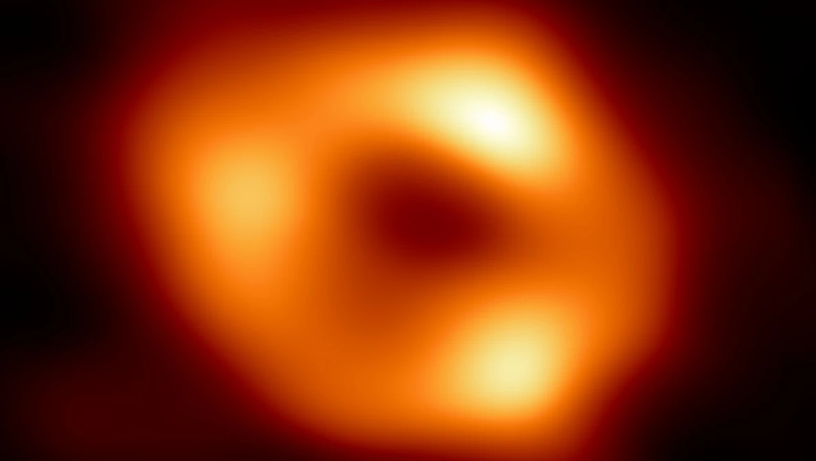 First photograph of a black hole, showing a glowing orange and red ring structure with a dark center.