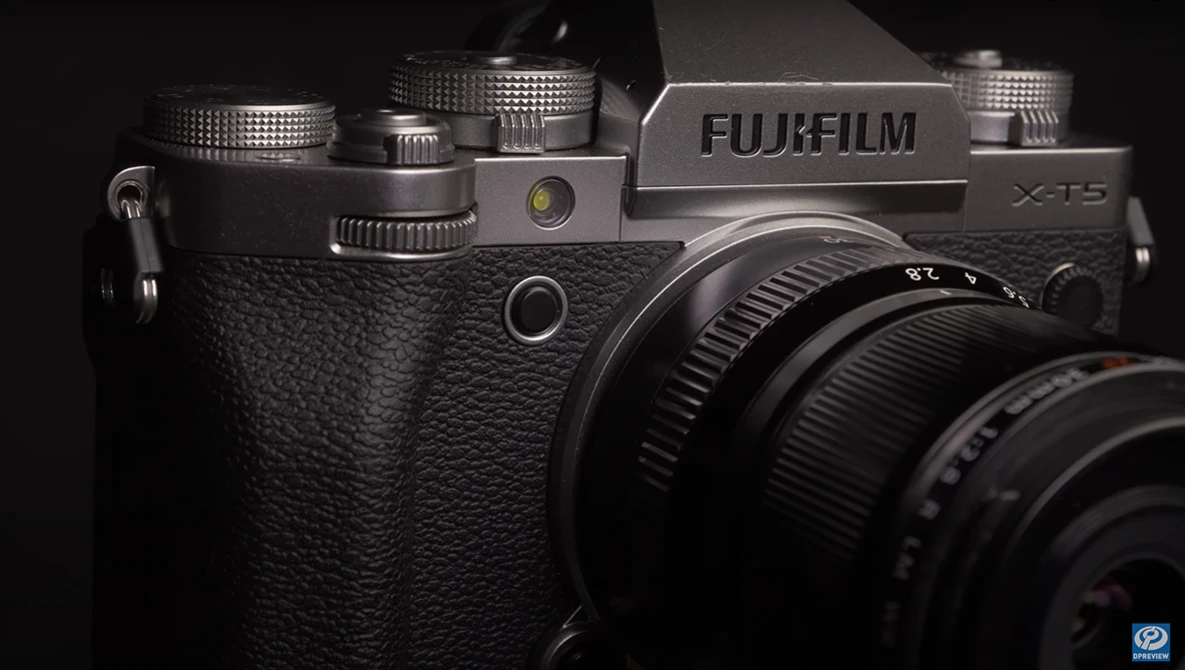 Fujifilm X-T5 camera with textured black body and attached lens, photographed against dark background.