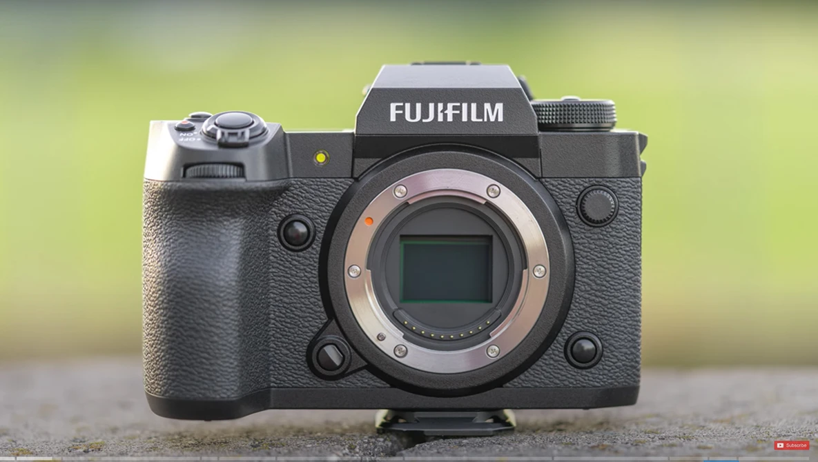 Fujifilm X-H2S mirrorless camera body with exposed sensor and lens mount against blurred green background.