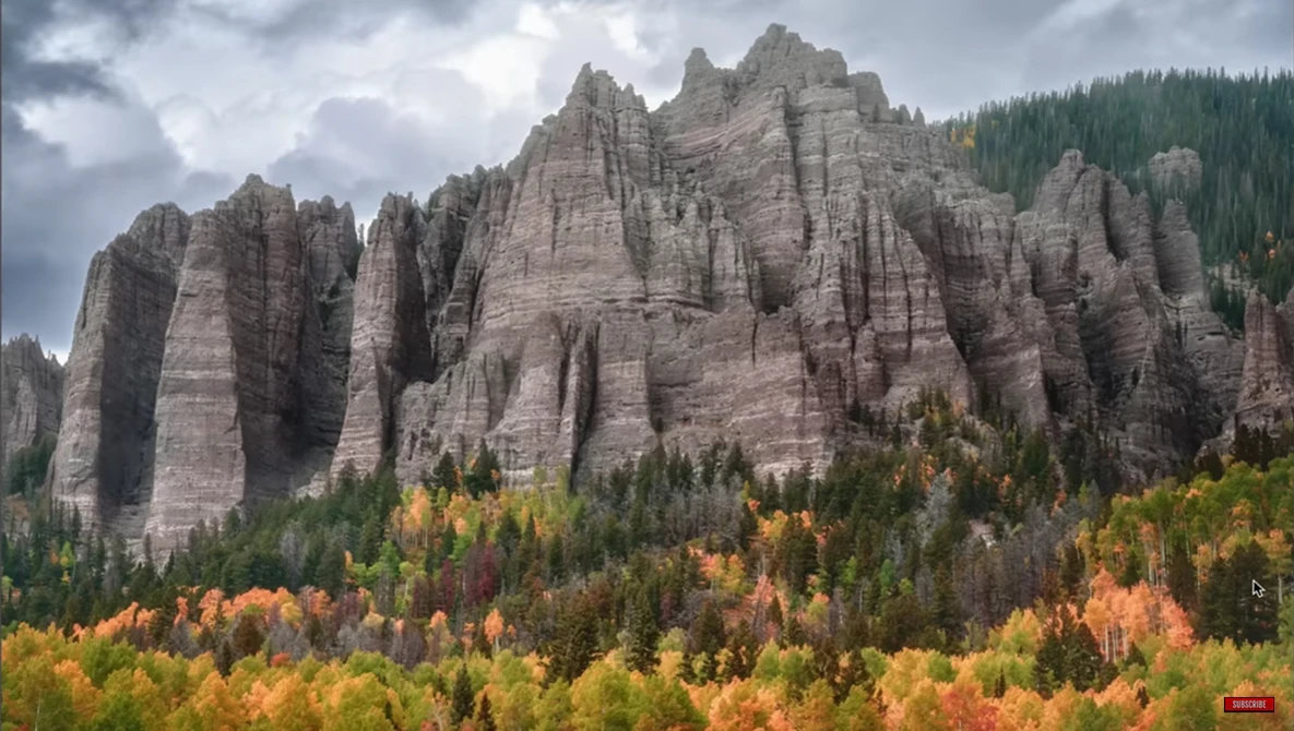 Dramatic columnar rock formations rising above a forested valley in autumn.