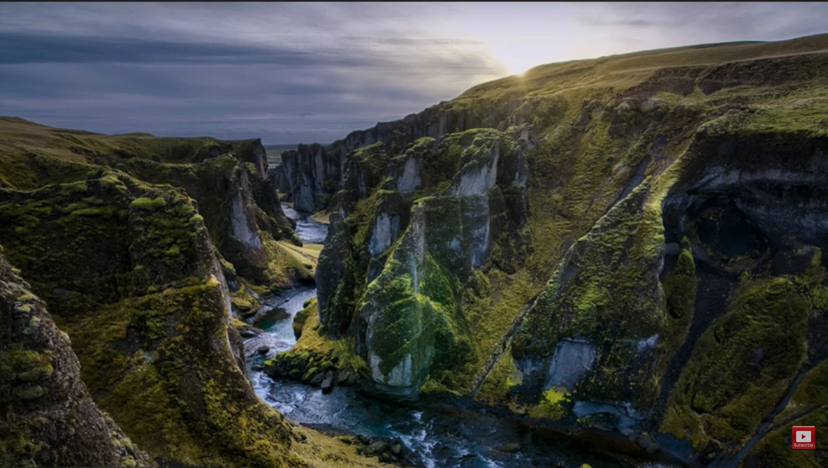 Deep canyon with moss-covered basalt cliffs and a winding river flowing through the valley floor.