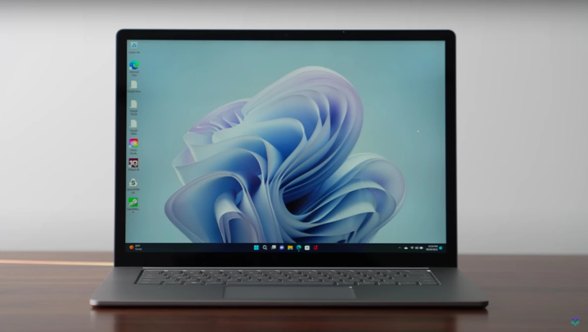 Screenshot of Windows 11 desktop displaying abstract blue and white fluid wallpaper on laptop screen.