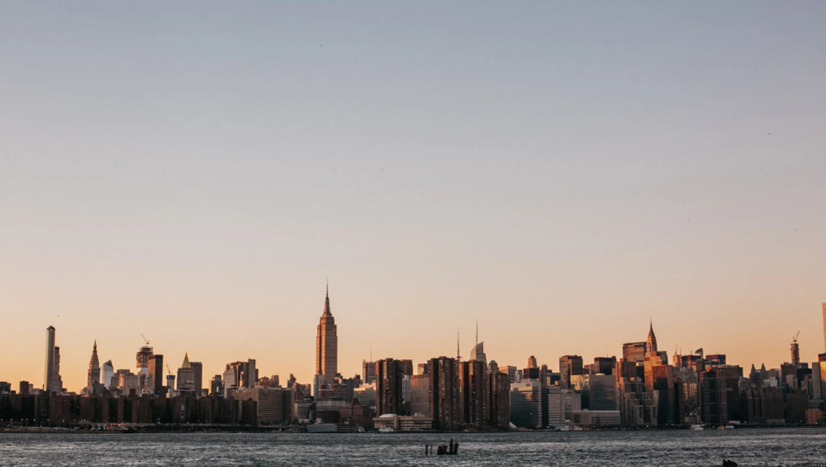Manhattan skyline at golden hour with Empire State Building prominently lit in center.