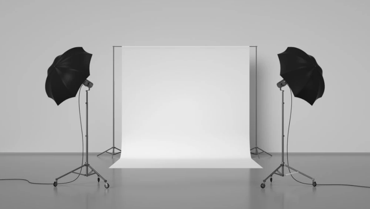 Professional studio setup with white seamless backdrop, two softbox umbrellas on tripod stands, and gray floor.