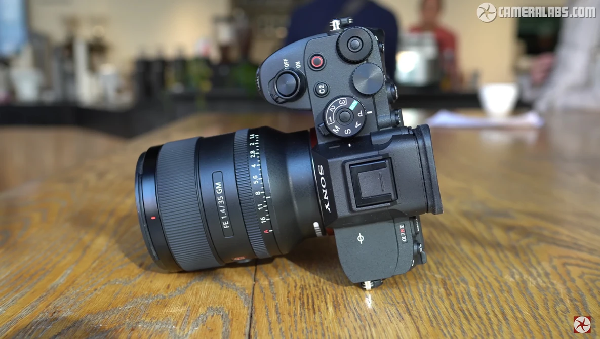 Mirrorless camera with attached prime lens mounted on wooden surface in indoor setting.