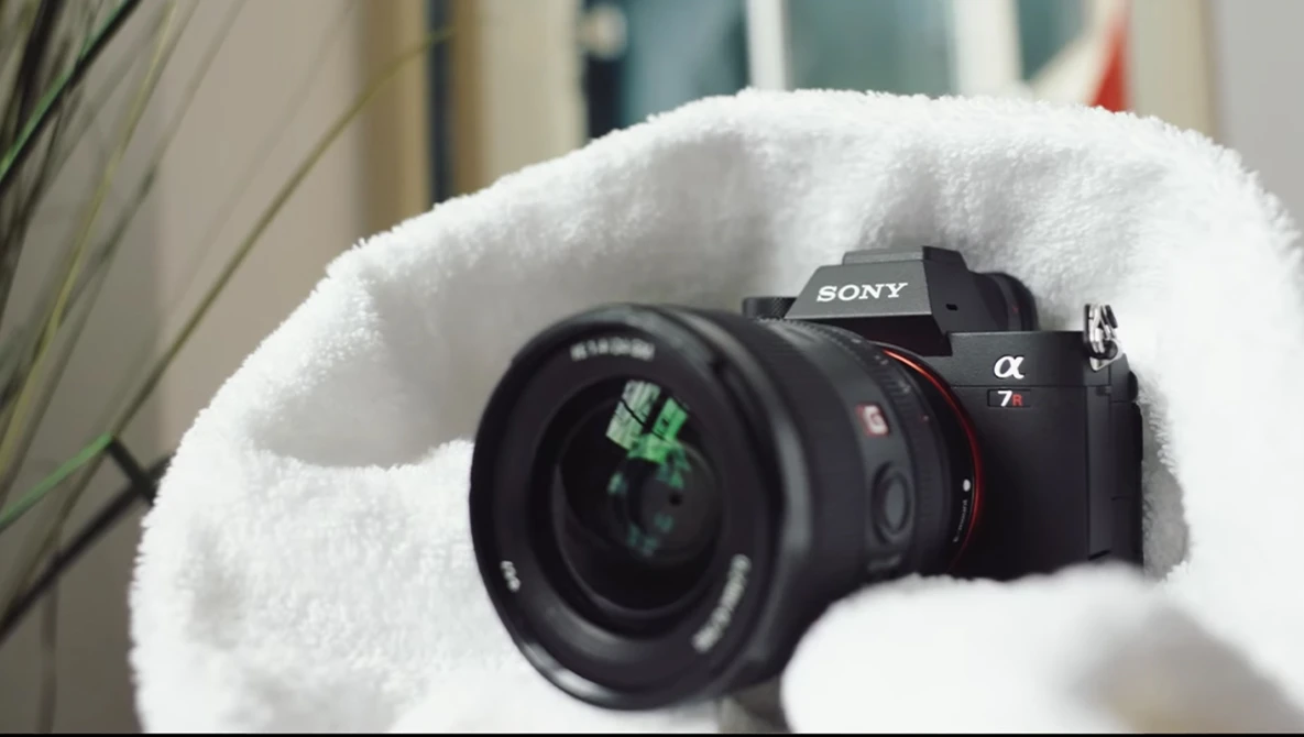 Sony α7 mirrorless camera with attached lens, cradled in white fluffy material.
