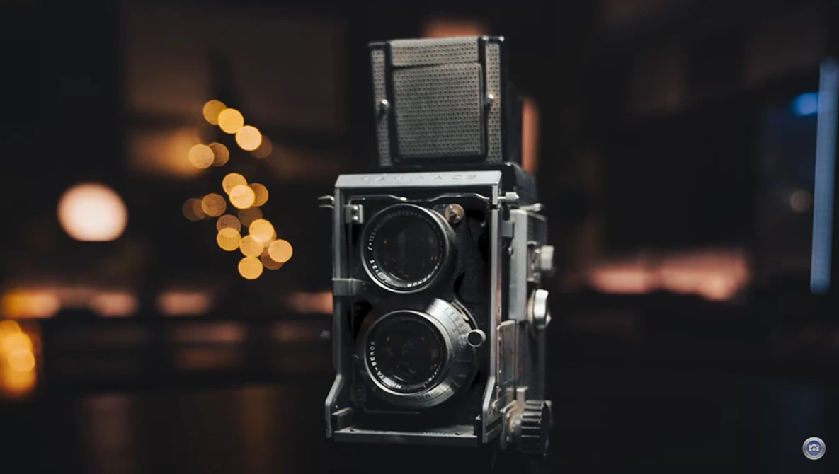 Vintage twin-lens reflex camera with folded viewfinder against blurred warm bokeh background.