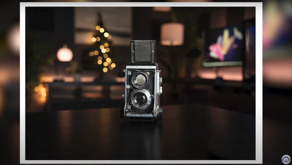 Vintage twin-lens reflex camera displayed on a dark surface with warm bokeh lights in the background.