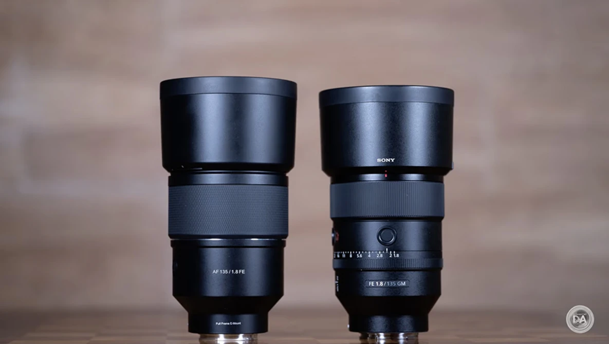 Two black telephoto lenses with lens hoods positioned side by side against a neutral beige background.