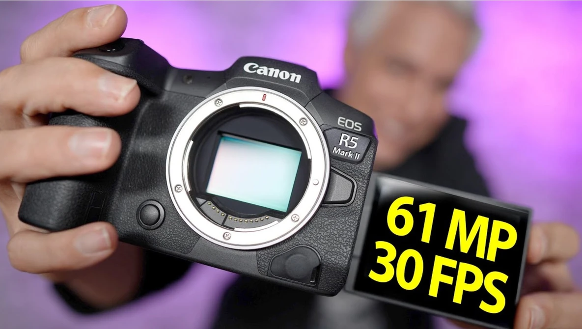 Canon EOS R5 Mark II camera body held in hands against purple background with specs overlay.