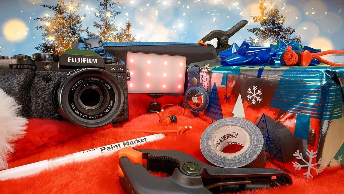 Fujifilm X-T5 camera with LED light and creative photography accessories arranged on red fabric with holiday decorations.