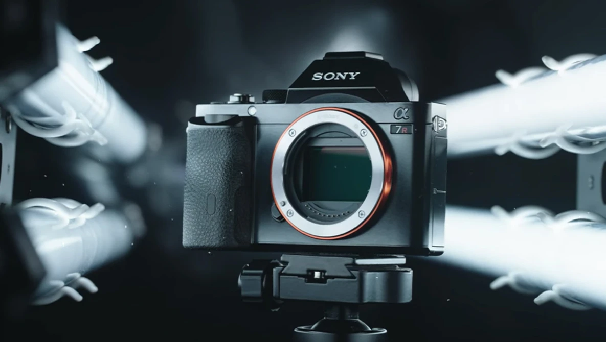 Sony mirrorless camera mounted on tripod with white feathers blurred in motion around it.