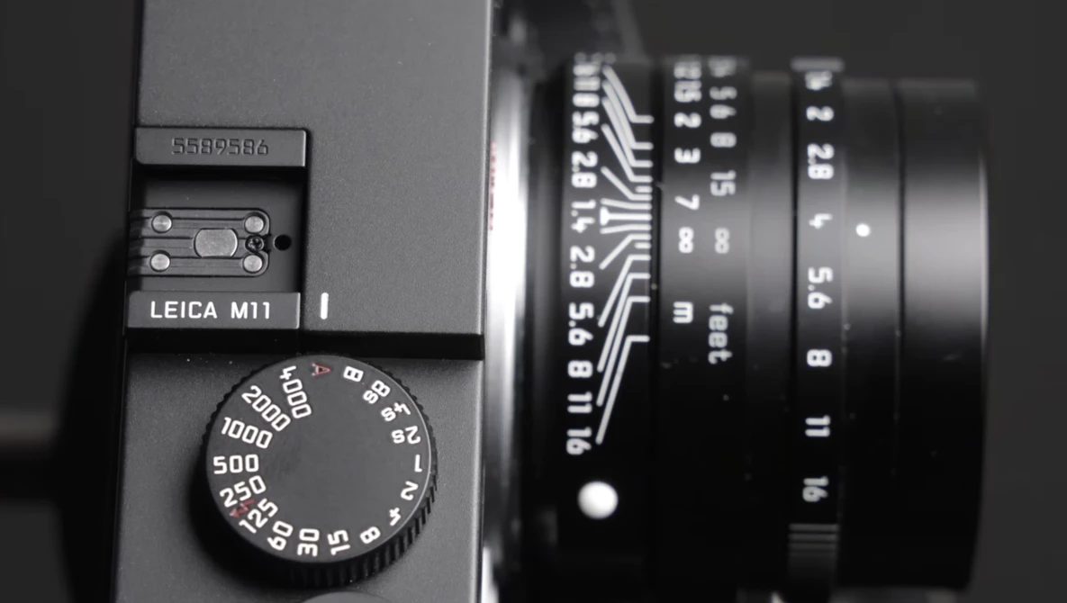 Leica M11 rangefinder camera with lens and shutter speed dial in black and white.