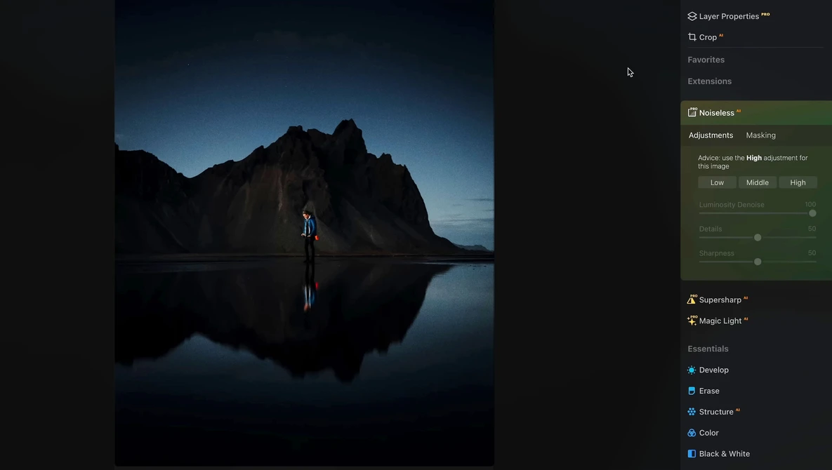 Silhouetted figure standing on reflective water with dramatic mountain backdrop at dusk.