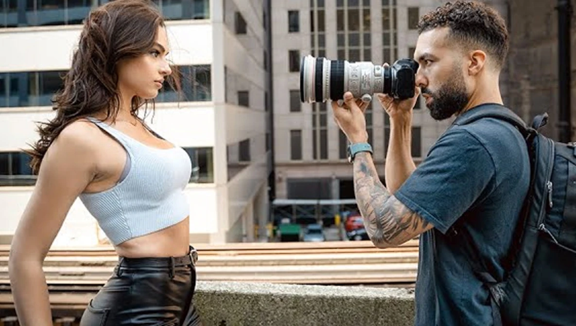 Photographer with telephoto lens shooting a portrait subject on an urban rooftop.