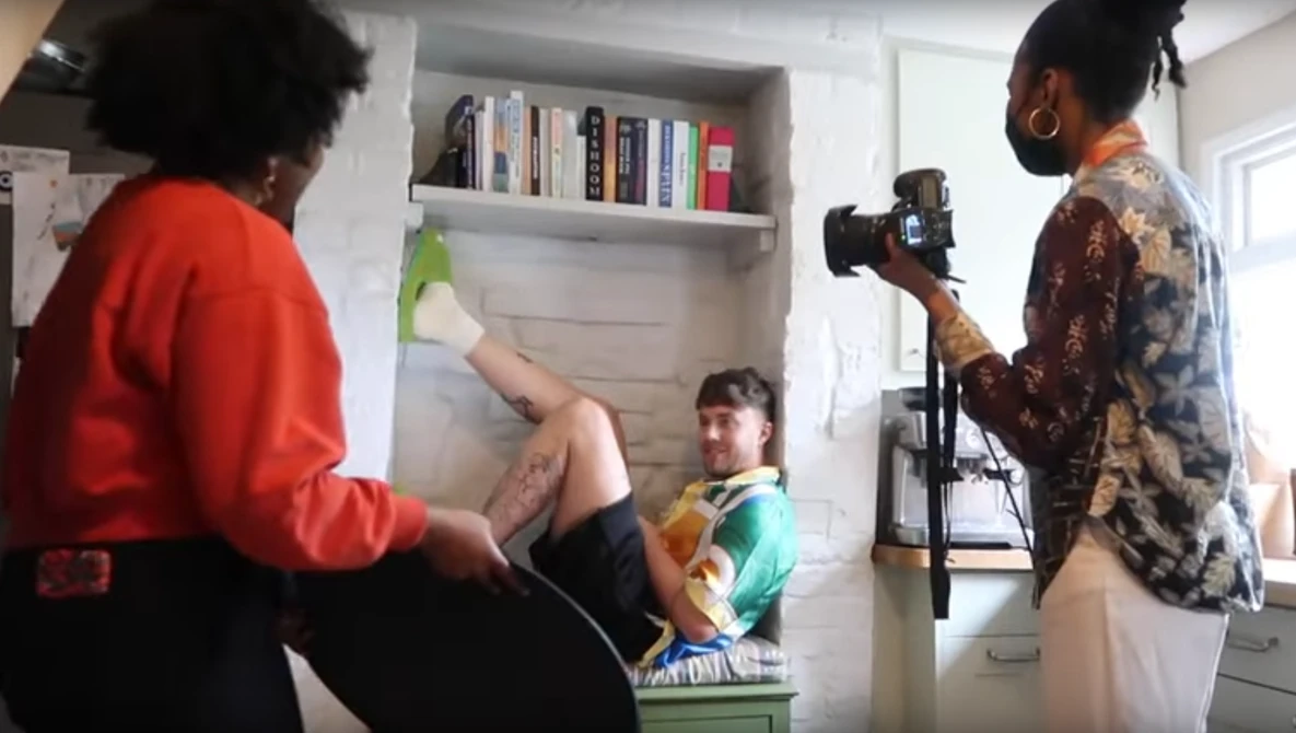 Behind-the-scenes photo shoot in a home interior with camera operator and lighting setup.