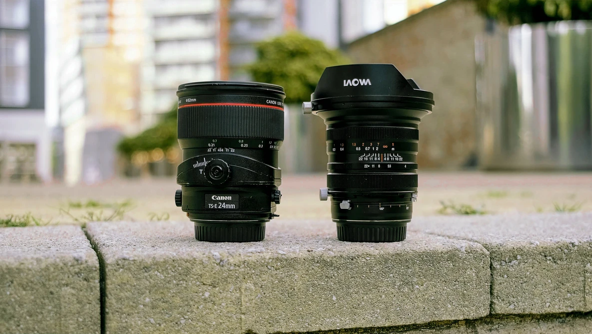 Three camera lenses arranged on a concrete ledge with urban buildings blurred in the background.