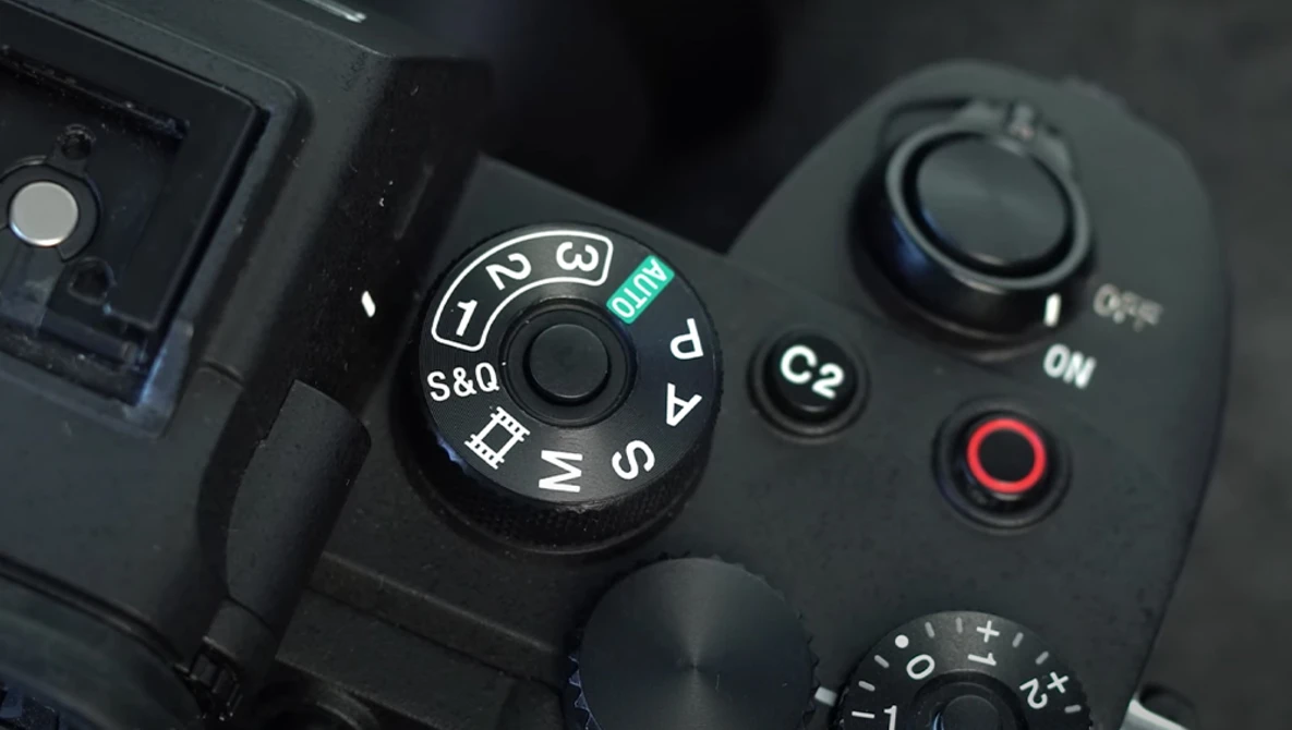 Close-up of a camera's mode dial and control buttons showing exposure compensation and shooting mode settings.