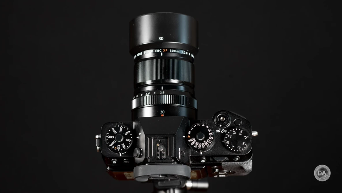 Top-down view of a vintage rangefinder camera with 30mm lens and mechanical controls against black background.
