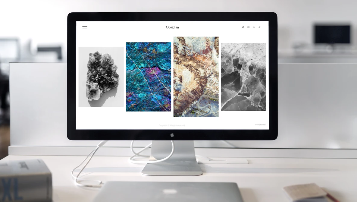Desktop monitor displaying a portfolio website with four landscape photographs arranged in a grid layout.