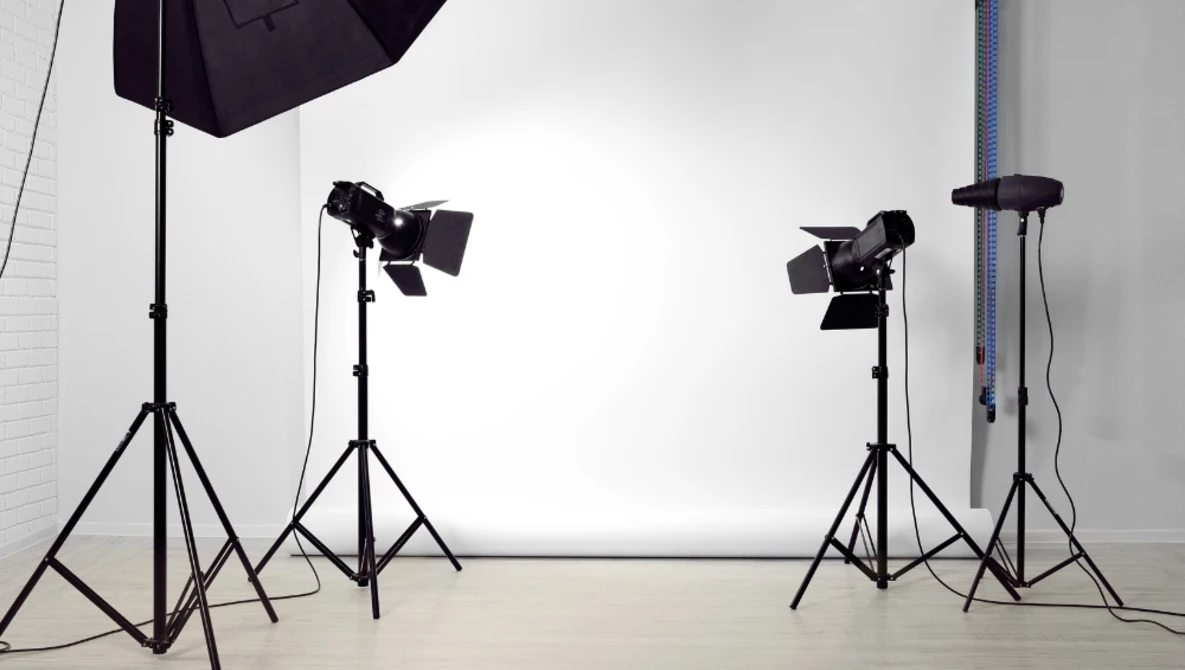 Professional studio setup with multiple tripod-mounted lighting fixtures and modifiers on a white cyclorama backdrop.