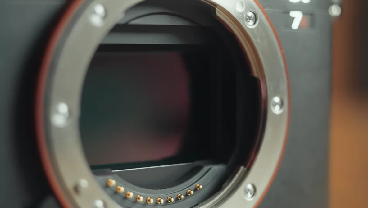 Camera body with open mirror box revealing the sensor and gold electrical contacts.