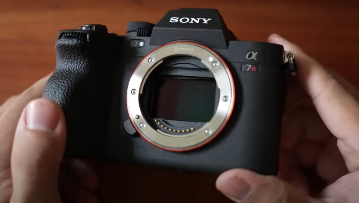 Sony a7r mirrorless camera held in hands, showing the open lens mount and sensor area.