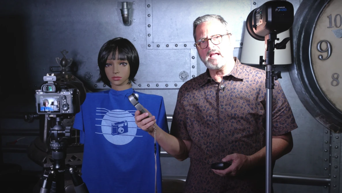 Two people in a studio setting with professional lighting equipment and a large clock visible in the background.