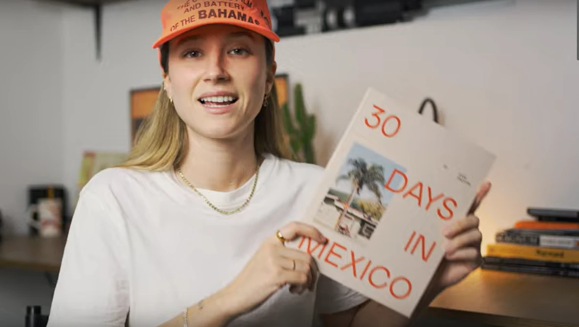 Woman holding a handmade sign reading "50 DAYS IN MEXICO" indoors.