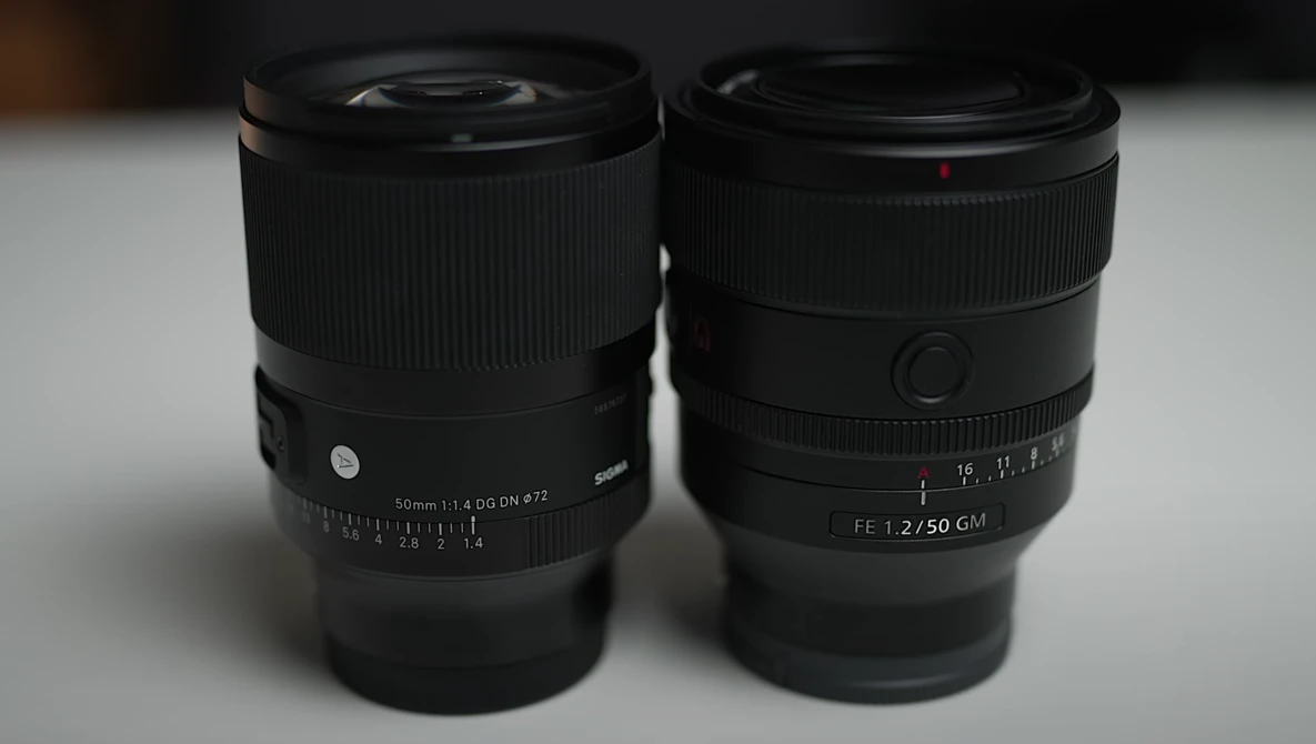 Two black prime lenses side by side on a white surface, displaying focal length markings and aperture rings.