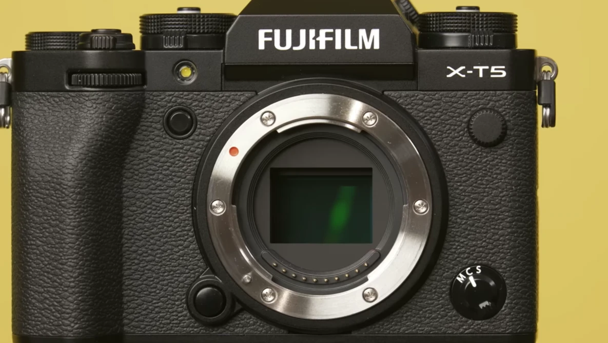 Fujifilm X-T5 mirrorless camera body against yellow background.