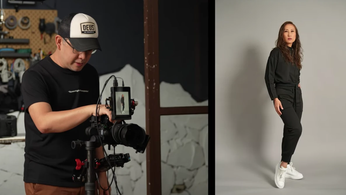 Filmmaker operating a gimbal-mounted camera system while a model poses in studio lighting.