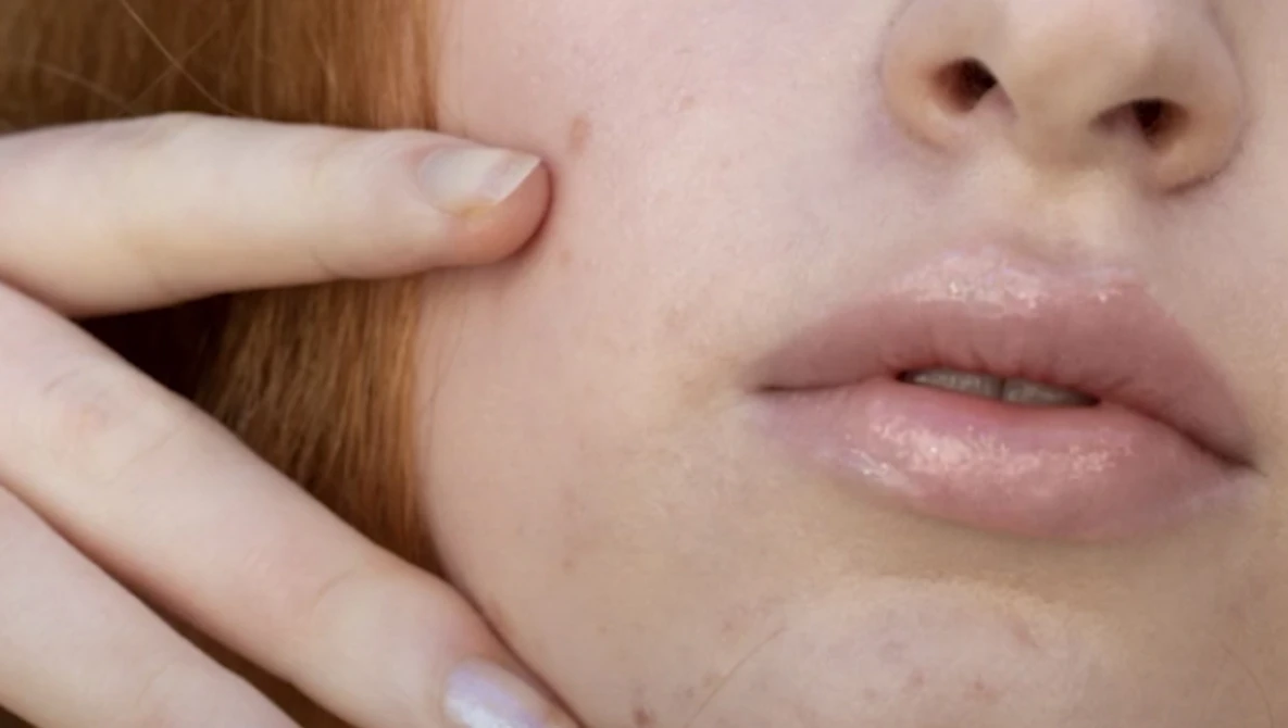 Close-up portrait showing smooth skin texture, soft natural lighting on face and neck.