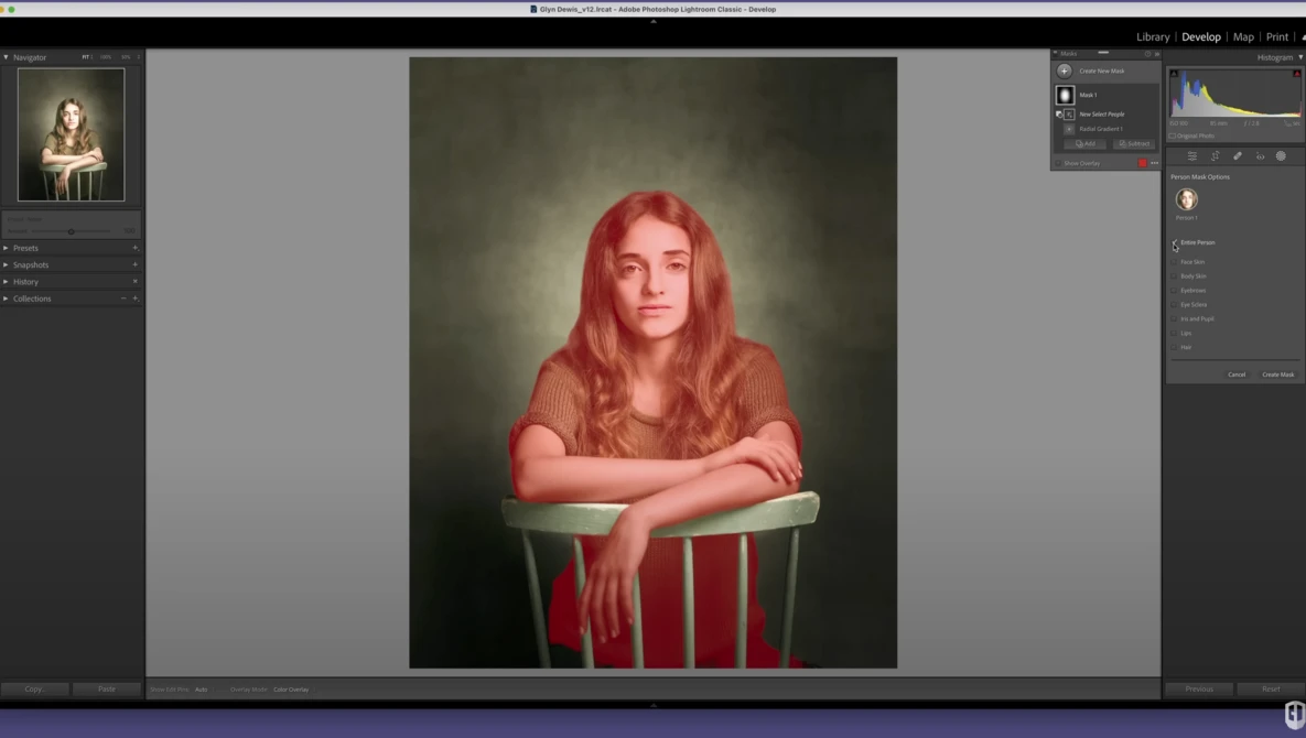 Portrait of a woman with long red hair seated in a red chair against a dark, textured background.