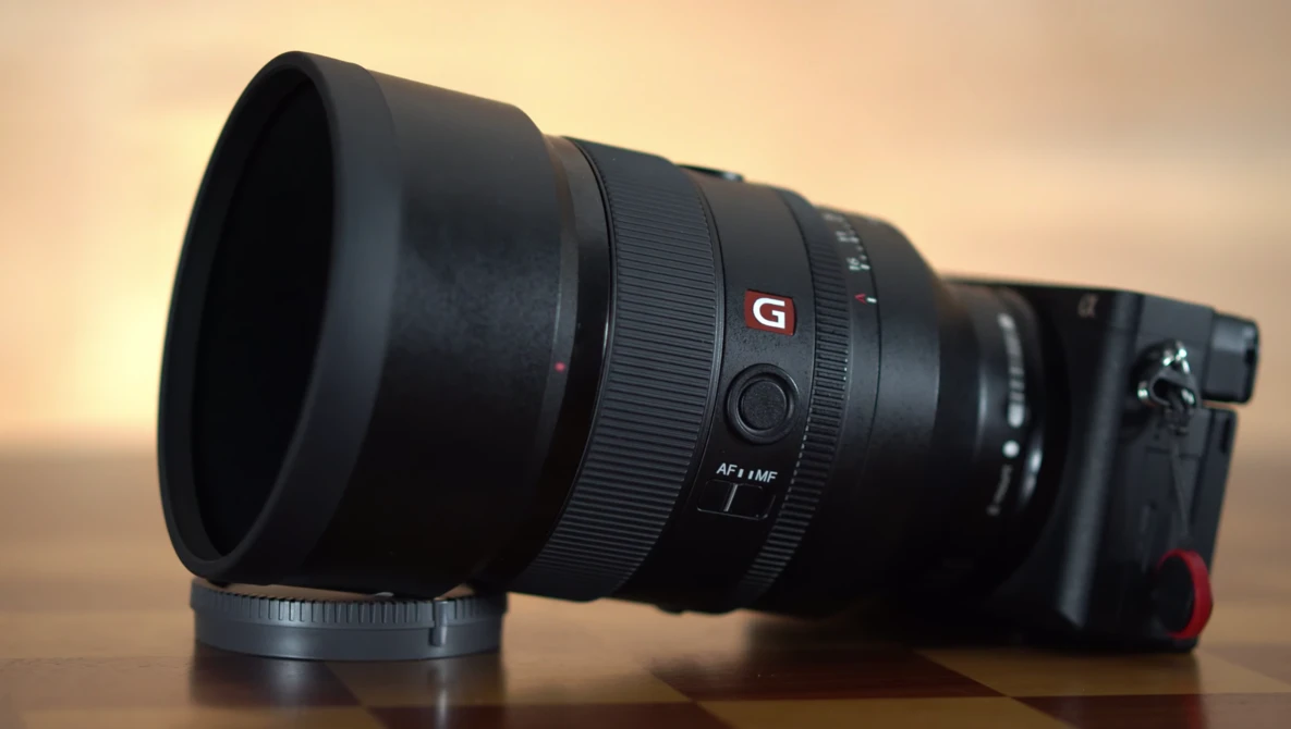 Sony G-series telephoto lens with lens hood attached mounted on mirrorless camera body.