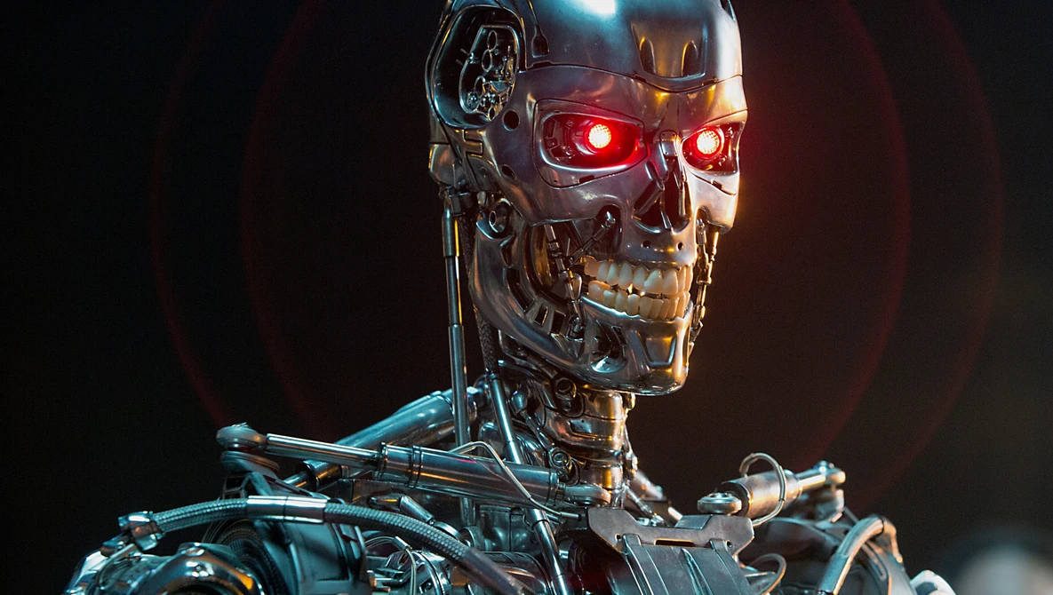 Close-up of a metallic humanoid robot head with glowing red eyes against a dark background.