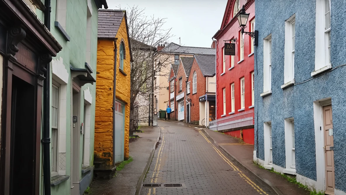 Narrow street lined with colorful historic buildings in various pastel hues including green, yellow, red, and blue.