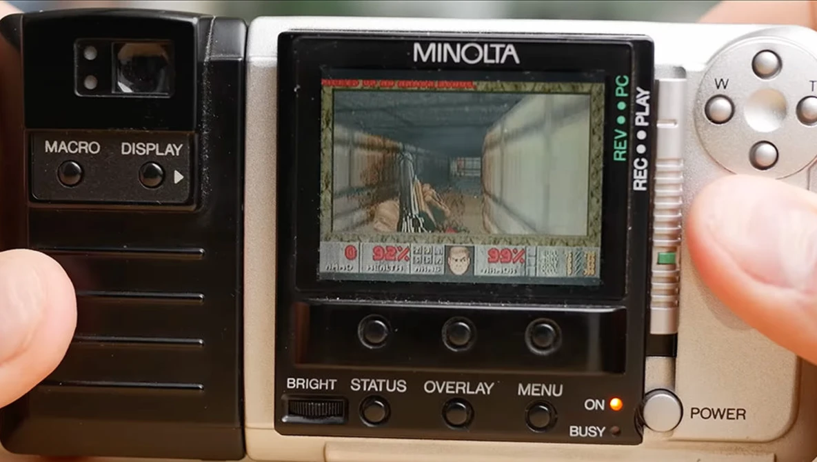 Three vintage Minolta cameras displayed side by side showing LCD screens and control buttons.
