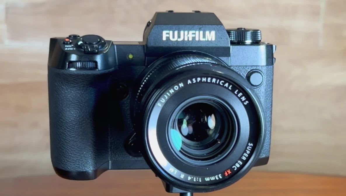 Fujifilm mirrorless camera with Fujinon aspherical lens mounted, displayed against a neutral background.