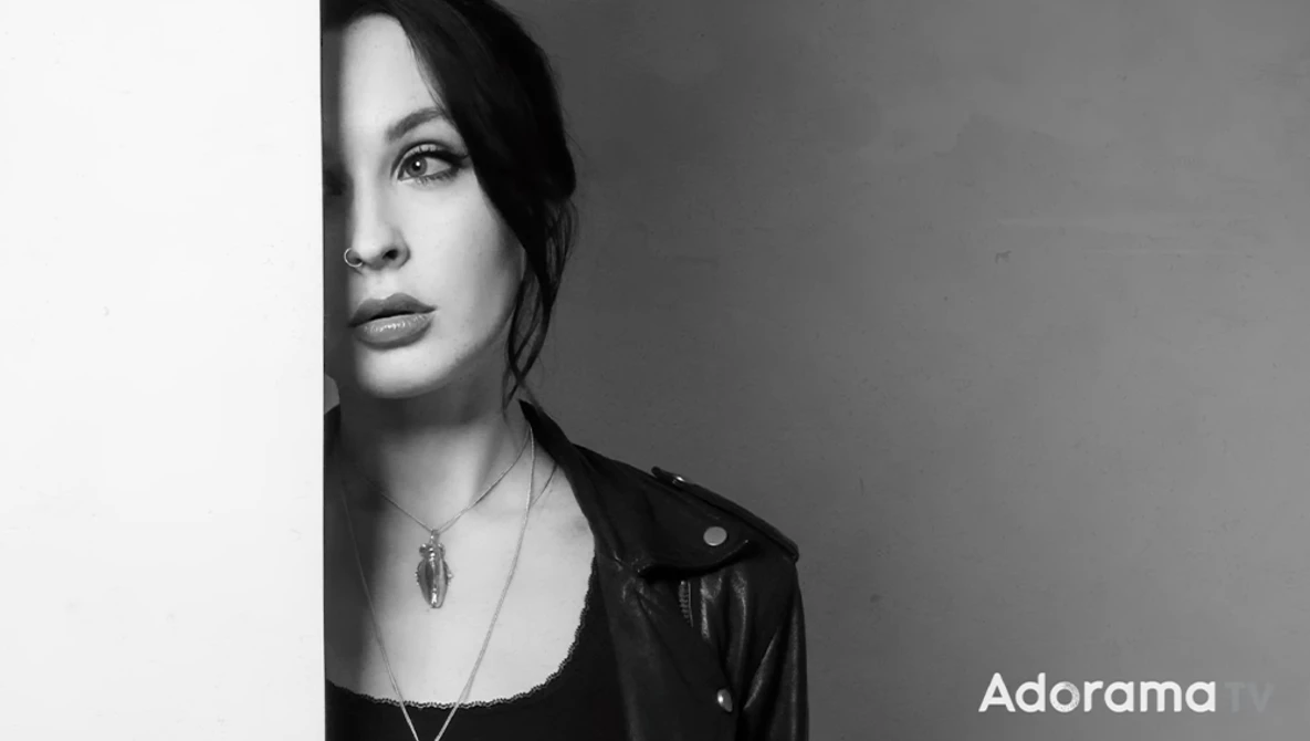 Woman's face in profile against a plain wall, rendered in high-contrast black and white.