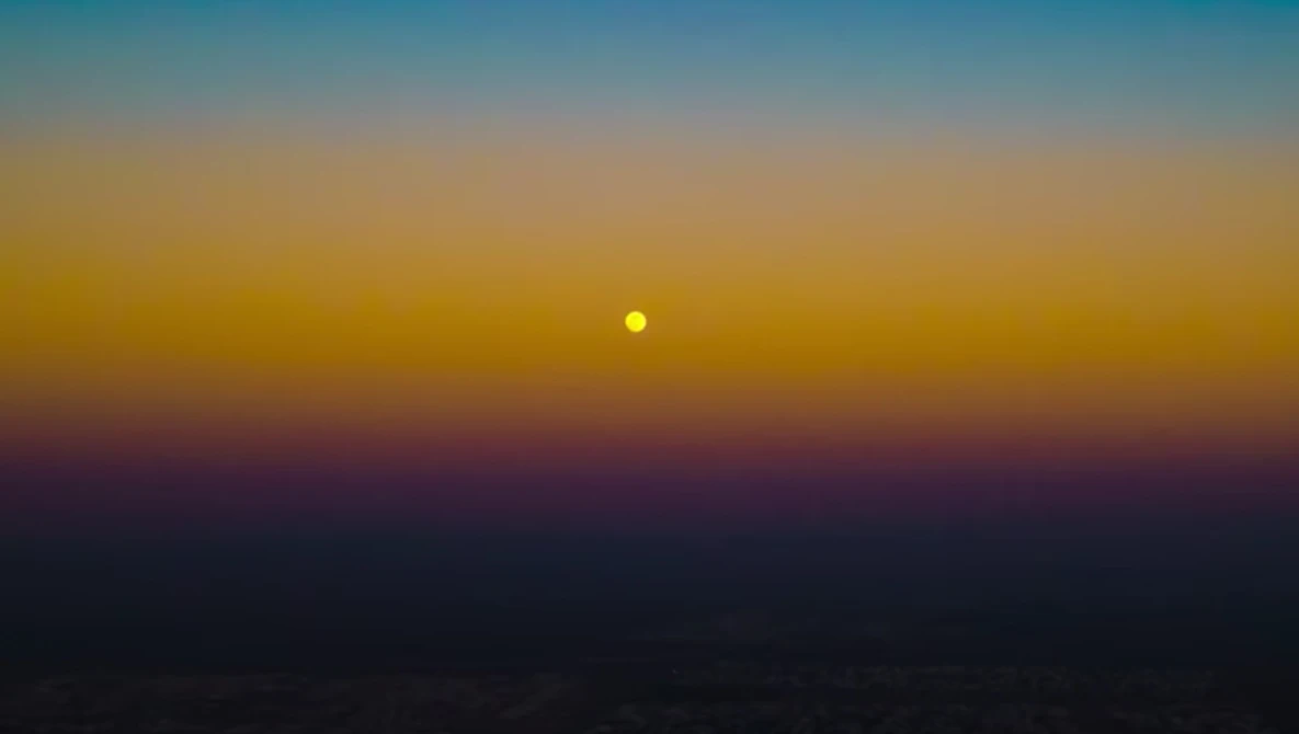 Sun positioned low on the horizon during golden hour with deep blue and purple tones in the sky.