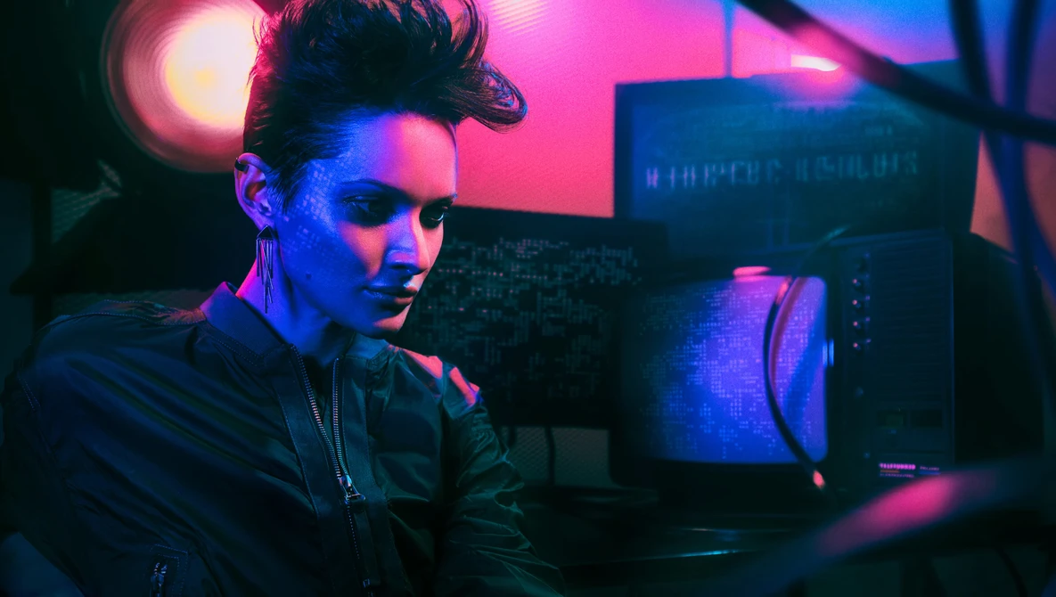 Person working at a computer workstation lit with vibrant pink and blue neon lights.