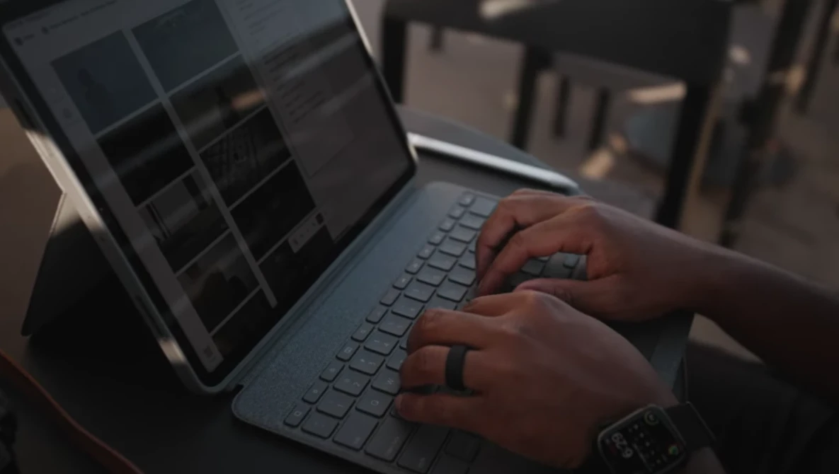 Hands typing on a laptop keyboard in outdoor sunlight with warm golden-hour lighting.