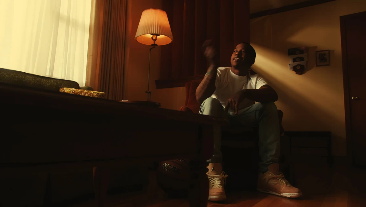 Person sitting on floor in warm interior lighting, gazing toward window light source.