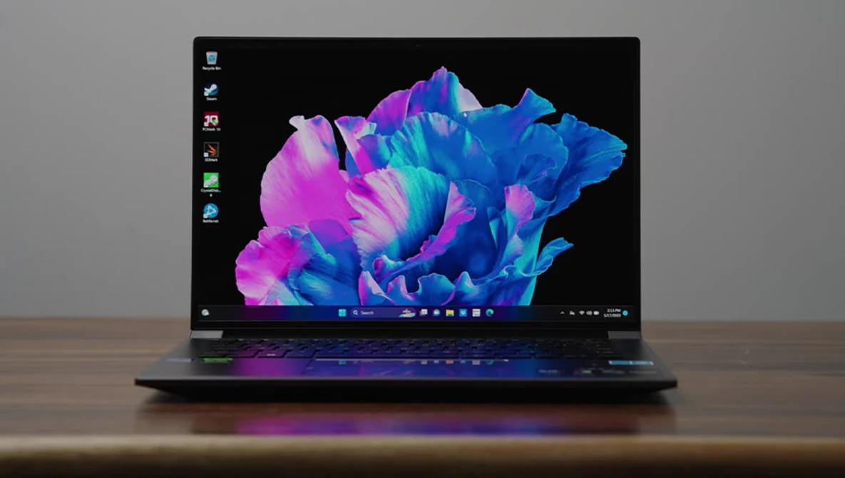 Laptop displaying vibrant blue and magenta abstract 3D rendered shapes on black background.