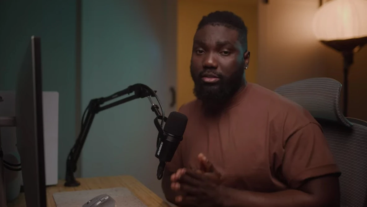 Man speaking into a microphone at a desk during a podcast or interview recording.