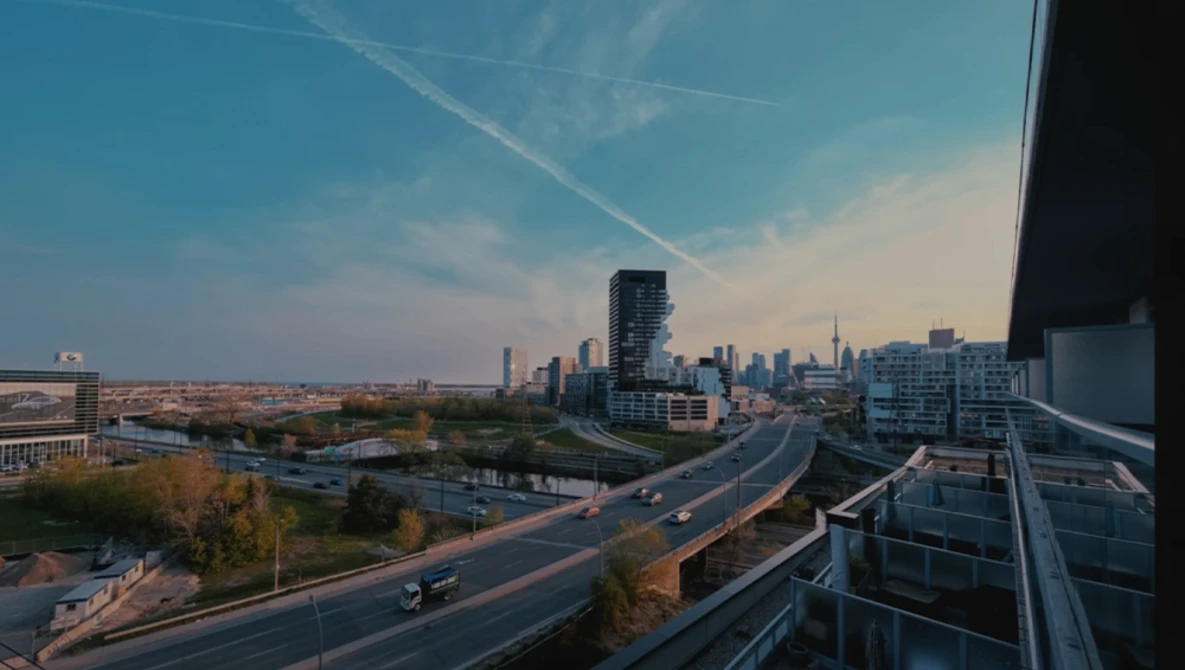Urban skyline with elevated highway and green park space during golden hour.