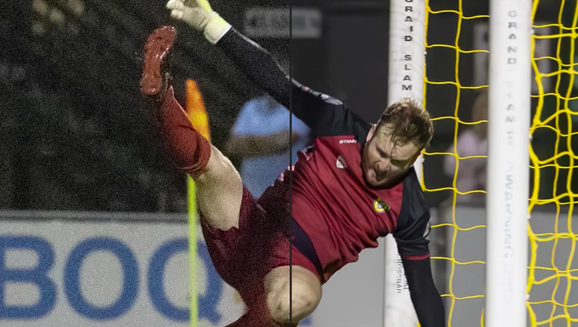 Soccer goalkeeper in maroon jersey diving horizontally to make a save, with yellow goal net visible behind.
