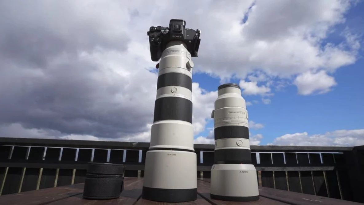 Two telephoto lenses with black and white striping displayed on a rooftop with a camera mounted on the taller lens.
